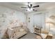 Bedroom with whimsical wallpaper, wooden crib, neutral tones, and ceiling fan at 9805 W Caron Dr, Peoria, AZ 85345