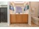 Well-lit bathroom features double sinks, tan tile floor, a dark storage cabinet, and white towel at 103 S Birdie Way, Casa Grande, AZ 85194