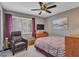 Cozy bedroom featuring a chair, ceiling fan, and window with plantation shutters at 10501 W Wilshire Dr, Avondale, AZ 85392