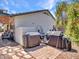Outdoor grill area with stone pavers, multiple grills covered for the season, and access to the backyard patio at 10501 W Wilshire Dr, Avondale, AZ 85392