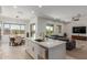 Open kitchen with white cabinets, center island, stainless steel appliances, and views of the dining and living areas at 11015 E Texas Ave, Mesa, AZ 85212
