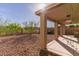 View of a private backyard featuring desert landscaping, a covered patio, and some green foliage at 118 N 223Rd Ave, Buckeye, AZ 85326
