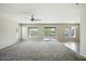 Bright and airy living room featuring neutral walls, carpet flooring, and large windows overlooking the backyard at 118 N 223Rd Ave, Buckeye, AZ 85326