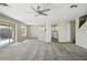 Bright and airy living room featuring neutral walls, carpet flooring, ceiling fan, and access to the backyard at 118 N 223Rd Ave, Buckeye, AZ 85326