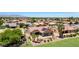 An aerial view of a desert home with a tile roof, solar panels, patio, and lush desert landscaping at 19745 N Mountain Sage Ln, Surprise, AZ 85374