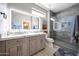 This bright bathroom features double sinks, a large illuminated mirror, and a tiled walk-in shower at 19745 N Mountain Sage Ln, Surprise, AZ 85374
