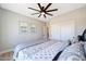 This bedroom offers light wood floors, ceiling fan, artwork and a comfy bedspread at 19745 N Mountain Sage Ln, Surprise, AZ 85374