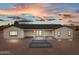 Rear view of house showcasing sliding glass doors, covered patio, and a backyard with a stone terrace at 28848 W Grand Ave, Wittmann, AZ 85361