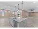 Bright kitchen boasts white cabinets, quartz counters and island, and herringbone wood floors at 28848 W Grand Ave, Wittmann, AZ 85361