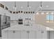 Bright kitchen boasts white cabinets, quartz counters, stainless appliances, and pendant lights at 28848 W Grand Ave, Wittmann, AZ 85361