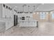 Bright kitchen boasts white cabinets, quartz counters and island, and herringbone wood floors at 28848 W Grand Ave, Wittmann, AZ 85361