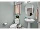 Powder room featuring a pedestal sink, round mirror, and decorative curtains at 3036 N Acacia Way, Buckeye, AZ 85396