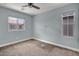 This bedroom features neutral carpet, a ceiling fan, and two windows at 3036 N Acacia Way, Buckeye, AZ 85396