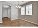 A dining room area with wood-look tile, neutral walls, two windows, and an elegant chandelier at 3036 N Acacia Way, Buckeye, AZ 85396