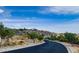 Scenic road leads to a hillside home with desert landscaping under a bright blue, partly cloudy sky at 3036 N Acacia Way, Buckeye, AZ 85396
