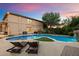 Beautiful backyard with a large, uniquely shaped pool, waterfall feature, and seating area at dusk at 3944 W Paradise Ln, Phoenix, AZ 85053