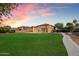 Expansive backyard with green lawn, mature trees, pool with waterfall, and solar panels on the roof at 3944 W Paradise Ln, Phoenix, AZ 85053