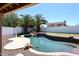 Backyard retreat showcasing a sparkling pool, rock features, and lush landscaping, perfect for relaxation at 6023 E Scafell Cir, Mesa, AZ 85215