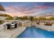 Scenic backyard featuring a pool with integrated waterfall, dining area, BBQ, and manicured desert landscaping at 7315 E Brisa Dr, Scottsdale, AZ 85266
