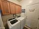 Functional laundry room with wooden cabinets, side-by-side washer and dryer, and an exterior door at 7722 E Wolf Canyon St, Mesa, AZ 85207