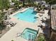 Aerial view of a community pool and hot tub with lounge seating and desert landscaping at 7955 E Chaparral Rd # 129, Scottsdale, AZ 85250