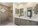 Elegant bathroom with double sinks, modern fixtures, neutral tiles, and a walk-in shower with a bench at 7955 E Chaparral Rd # 129, Scottsdale, AZ 85250