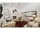 Bright living room with a fireplace, white beamed ceilings, and large windows with plantation shutters at 7955 E Chaparral Rd # 129, Scottsdale, AZ 85250