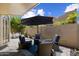 Inviting outdoor patio seating area with comfortable wicker chairs, plush blue cushions, and a large sun umbrella at 7955 E Chaparral Rd # 129, Scottsdale, AZ 85250