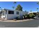 Inviting mobile home featuring lush landscaping, a screened-in porch, and a serene desert setting with palm trees at 111 S Greenfield -- # 602, Mesa, AZ 85206