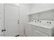 A clean, white laundry room featuring a side-by-side washer and dryer and a shelf for storage at 1373 S Vista Ave, Florence, AZ 85132