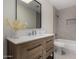 Modern bathroom featuring a wood vanity, black framed mirror, and tiled bathtub at 18610 N 45Th Ave, Glendale, AZ 85308