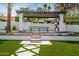 Charming pergola with outdoor dining area set amidst lush artificial turf and patterned pavers in the backyard at 1925 E Lane Ave, Phoenix, AZ 85020