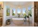 Bright bathroom featuring a soaking tub beneath a window and white stone counters at 21105 N 37Th Run, Phoenix, AZ 85050