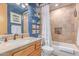Stylish bathroom features a tiled shower with a decorative niche, natural stone surfaces, and blue accent wall at 2129 E Beautiful Ln, Phoenix, AZ 85042