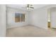 Spacious bedroom with neutral carpet, a ceiling fan, large window and an adjacent bathroom at 2861 E Morenci Rd, San Tan Valley, AZ 85143