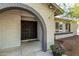 Close-up of a front porch with an arched entryway, a security screen door, and blooming flowerpots at 3061 W Betty Elyse Ln, Phoenix, AZ 85053