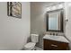 Cozy half bath with decorative wallpaper, framed mirror, and dark wood vanity at 3062 E Cullumber St, Gilbert, AZ 85234
