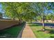 A serene view of the neighborhood sidewalk lined with mature trees and a low privacy wall at 3062 E Cullumber St, Gilbert, AZ 85234