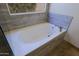 Close-up of a bathtub with stone tile surround, chrome faucet and window at 32710 N 71St St, Scottsdale, AZ 85266