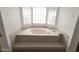 Bright bathroom featuring a soaking tub with tiled surround and a glass-block window at 3314 E Draper Cir, Mesa, AZ 85213