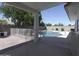 Covered patio view of the swimming pool, block fence, and lush backyard landscaping at 3314 E Draper Cir, Mesa, AZ 85213