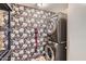 This stylish laundry room boasts a floral accent wall, modern stacked washer/dryer, and storage shelves at 3344 N 62Nd Pl, Scottsdale, AZ 85251