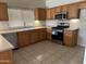 Well-lit kitchen features stainless steel appliances, wooden cabinetry, and neutral countertops, perfect for cooking at 45091 W Gavilan Dr, Maricopa, AZ 85139
