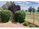 Well-maintained landscaping with green bushes and golf course views beyond a wrought iron fence at 8541 E Krail St, Scottsdale, AZ 85250