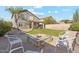 Backyard with a stone fire pit surrounded by comfortable seating, lawn, and privacy fence at 10252 E Butherus Dr, Scottsdale, AZ 85255
