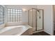 A luxurious bathroom features a soaking tub, separate glass shower, and natural light from glass block window at 12935 E Mercer Ln, Scottsdale, AZ 85259