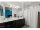 A well lit main bathroom featuring double sinks, dark wood cabinetry and a walk in shower at 17038 W Mohave St, Goodyear, AZ 85338
