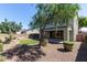 Gravel backyard featuring a small grass area, lush greenery, and a covered patio at 17154 W Las Palmaritas Dr, Waddell, AZ 85355