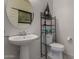 Modern bathroom featuring pedestal sink, round mirror, and minimalist shelving for storage at 17946 W Via Del Sol --, Surprise, AZ 85387