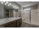 Bathroom featuring a double sink vanity, glass enclosed shower with a bench, and a large mirror at 18766 N Salerno Dr, Maricopa, AZ 85138